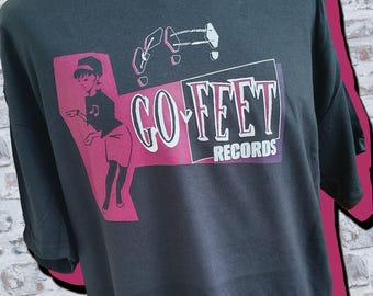 Puede incluir: Camiseta negra con un gráfico rosa de una mujer bailando y el texto "GO-FEET RECORDS".