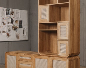 May include: Wooden storage cabinet with a light brown finish. The cabinet has a rounded top and bottom, with open shelves and doors with woven cane inserts. The cabinet is part of a furniture set. The brand name "Oaky Oak Furniture" is visible.