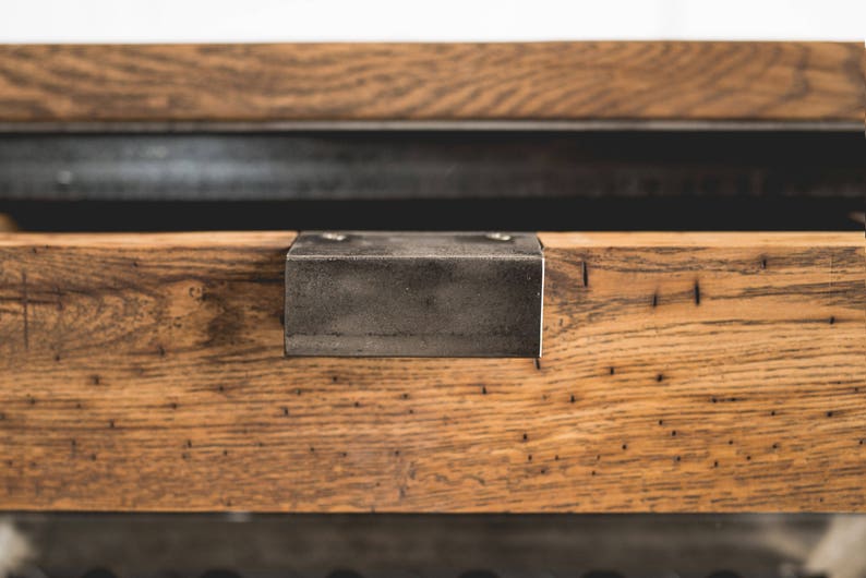 Puede incluir: Primer plano de una secci&oacute;n de mesa de madera con un soporte met&aacute;lico. La madera tiene una veta natural y un color marr&oacute;n c&aacute;lido. El soporte met&aacute;lico es rectangular y se fija con dos tornillos.