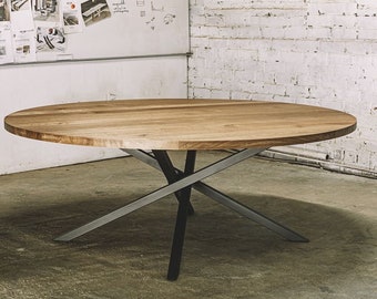 May include: A round wooden dining table with a light brown finish. The table has a unique base made of crisscrossing metal supports in a silver-gray color, with a black central column. The table is a modern design.