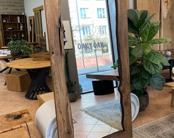 May include: A large, rectangular mirror with a natural wood frame. The frame has a raw, organic edge, showcasing the wood's grain and knots. The mirror reflects a room with a window displaying the text "Oaky Oak".