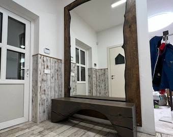 Op de afbeelding: Een grote, rechthoekige spiegel met een donkerhouten frame en een bijpassende bank. De spiegel is aan een witte muur bevestigd en de bank staat eronder. De vloer is gemaakt van lichtgekleurde houten planken. De tekst "OAKY OAK furniture" staat linksboven.