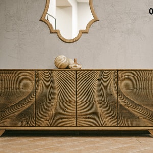 Puede incluir: Un aparador de madera con un patrón único en forma de onda en las puertas. El mueble es de color marrón cálido y tiene cuatro puertas. Hay objetos decorativos encima y un espejo colgado arriba. El logotipo "Oaky Oak Furniture" es visible.