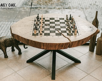 May include: A unique chess table made from a cross-section of a tree trunk. The light-colored wood top features a black and white chess board and is supported by a black metal base. The table is surrounded by decorative items.