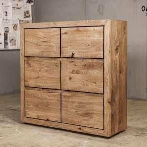 Puede incluir: Un mueble de madera marrón claro con seis cajones cuadrados. El mueble tiene un acabado de vetas de madera natural y está etiquetado como "Oaky Oak furniture" en la esquina superior derecha. El mueble es de estilo moderno.