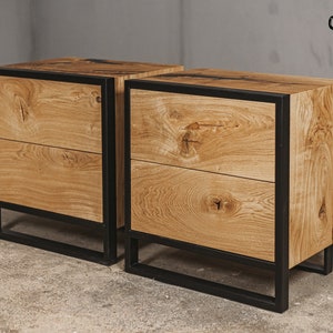 Peut inclure: Deux tables de chevet en bois, chacune avec deux tiroirs. Les tables sont en bois clair avec un motif de grain naturel. Elles ont des cadres en métal noir et le texte "Oaky Oak furniture" en haut à droite.