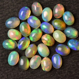 May include: A collection of oval-shaped opal gemstones in various shades of green, blue, and yellow. The opals are arranged in a loose cluster on a dark background.
