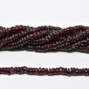 May include: Strands of dark red garnet gemstone beads. The beads are small, irregular chips with a polished, glossy finish. The beads are strung together, creating a textured and rich appearance, perfect for jewelry making.