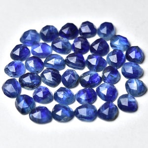 May include: A collection of 25 faceted blue kyanite gemstones. The stones are a deep blue color and have a variety of shapes and sizes.
