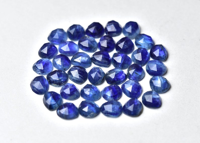 May include: A collection of 25 faceted blue kyanite gemstones. The stones are a deep blue color and have a variety of shapes and sizes.