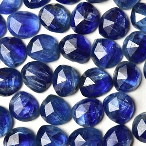 May include: A collection of blue kyanite gemstones, each with a faceted, irregular shape. The stones have a deep blue color with a slight shimmer.