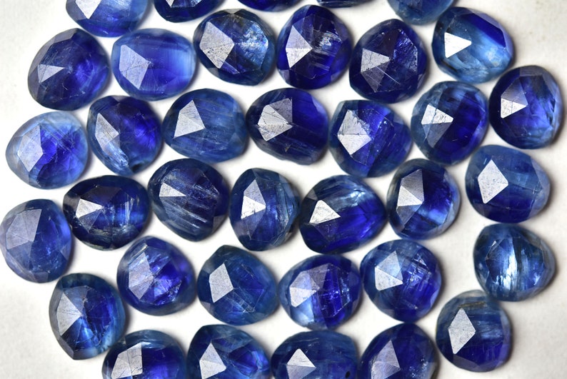 May include: A collection of blue kyanite gemstones, each with a faceted, irregular shape. The stones have a deep blue color with a slight shimmer.