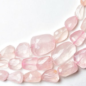 May include: Strands of faceted rose quartz beads in varying shapes and sizes. The beads are a soft pink color and are strung together, creating a necklace or bracelet design. The background is white.