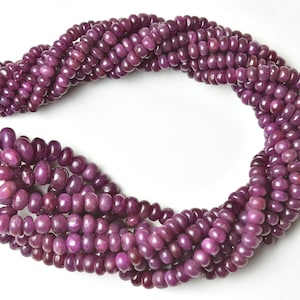 May include: A strand of purple ruby beads, approximately 4mm in size, with a smooth, polished finish. The beads are strung on a clear thread and are arranged in a loose, flowing pattern.