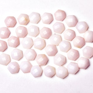 May include: A collection of 30 pink opal cabochons, each with a faceted hexagonal shape. The cabochons are arranged in a loose circle on a white background.