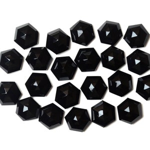 May include: A collection of 20 black, faceted, hexagonal-shaped glass stones. The stones are arranged in a random pattern on a white background.