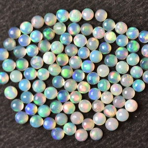 May include: A collection of round, iridescent opal gemstones in various shades of white, blue, and green. The opals are approximately 4mm in diameter and have a smooth, polished finish.