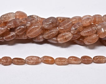 May include: A strand of translucent, light brown, oval-shaped gemstone beads. The beads have a slightly cloudy appearance with subtle brown and white inclusions.