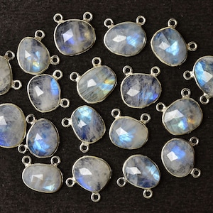 May include: A collection of 18 silver-toned gemstone pendants with a pearlescent white finish and iridescent blue hues. Each pendant has two jump rings for attaching to jewelry.