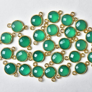 May include: A collection of 20 green gemstone beads with gold-toned jump rings. Each bead has a faceted surface and is approximately 10mm in diameter.