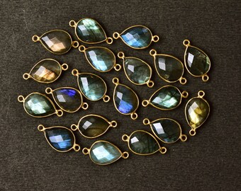 May include: A collection of 18 teardrop-shaped labradorite gemstone pendants with gold-toned jump rings. The stones are a mix of blue, green, and gold.