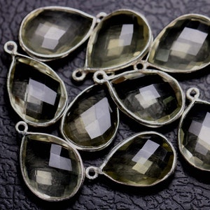 May include: A group of eight teardrop-shaped, faceted, clear quartz crystal pendants with silver-toned metal bail loops.