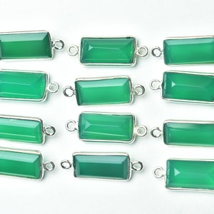 May include: Rectangular green gemstone connectors with a silver-colored metal frame. Each connector has a bright green, faceted gemstone and small loops on each end for attaching to other components. The gemstones are set against a white background.