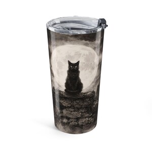 May include: A cylindrical stainless steel tumbler with a clear plastic lid featuring a graphic print of a black cat sitting on a stone wall against a large, pale full moon. The background is dark and moody with shades of gray, black, and white.