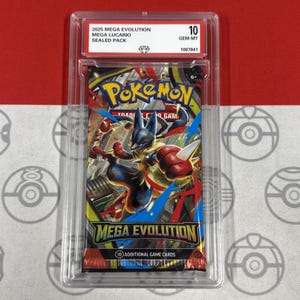 Puede incluir: Un paquete sellado de cartas coleccionables Pokémon Mega Evolution con Lucario, calificado como 10 GEM-MT. El paquete está dentro de un protector transparente, con el texto "2025 MEGA EVOLUTION MEGA LUCARIO SEALED PACK" visible.