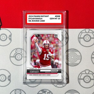 May include: A 2024 Panini Instant trading card featuring Dylan Raiola, a Nebraska Cornhuskers quarterback, in a red jersey with the number 15. The card is graded GEM MT 10 and is a NIL Rookie Card.