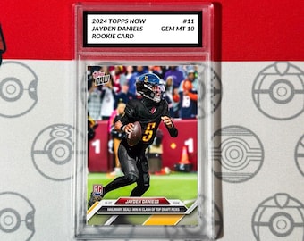 Peut inclure: Une carte de recrue Topps Now 2024 représentant Jayden Daniels, un joueur de football américain portant un uniforme noir et or avec le numéro 5. La carte est classée GEM MT 10 et est numérotée #11. La carte présente une photo de Daniels en action sur le terrain, avec le texte "Hail Mary Seals Win in Clash of Top Draft Picks" sous la photo.
