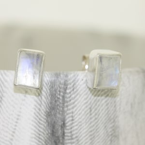 Puede incluir: Un par de pendientes de plata con engastes cuadrados de piedra lunar.