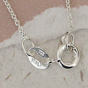 May include: Close-up of a silver chain necklace clasp with a 925 Italy stamp.