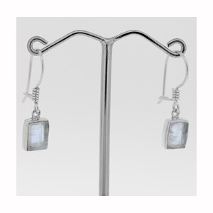 May include: A pair of silver dangle earrings with square-shaped white moonstone gemstones.