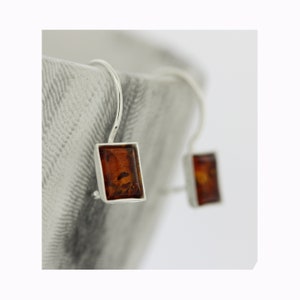 May include: A pair of silver dangle earrings with rectangular amber stones.
