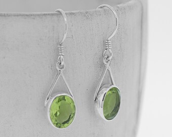 Peut inclure: Une paire de boucles d'oreilles pendantes en argent avec des gouttes de pierres précieuses vertes. Les boucles d'oreilles ont un design triangulaire et sont suspendues à un crochet.