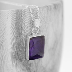 May include: A silver chain necklace with a square pendant featuring a deep purple amethyst gemstone.
