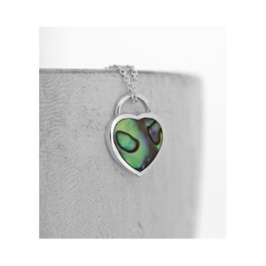 Può includere: Una collana d'argento con un ciondolo a forma di cuore con un'intarsio di madreperla verde e blu.