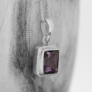 Könnte beinhalten: Eine silberne Halskette mit einem quadratischen Anhänger aus Amethyst.