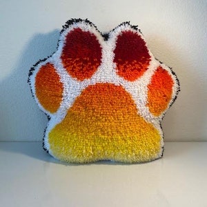 May include: A plush paw print shaped pillow with a white center and red, orange, and yellow accents.