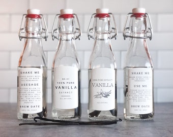 May include: Four glass bottles with labels that say "100% Pure Vanilla Extract" and "Shake Me" with instructions for use and a brew date. The bottles are filled with a clear liquid and have a red and silver bottle stopper.  A vanilla bean is in front of each bottle.