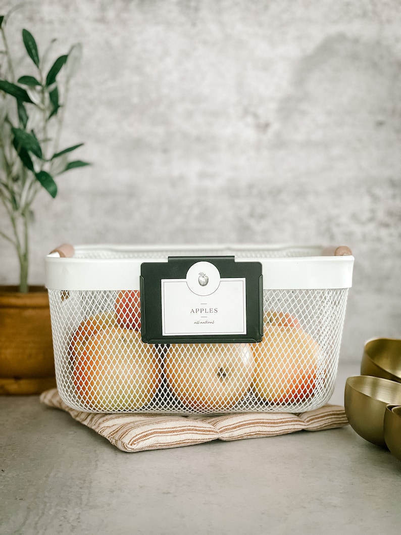 May include: White wire mesh basket with black label that says "APPLES all natural" and filled with red apples. The basket is sitting on a brown and white striped fabric mat.