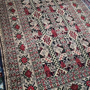 Könnte beinhalten: Ein traditioneller Teppich mit einem geometrischen Muster in Rot-, Grün-, Blau- und Beigetönen. Der Teppich hat einen Fransenrand.