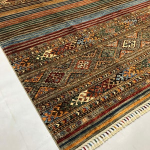 May include: A colorful rug with a geometric pattern and fringe. The rug has a variety of colors, including red, blue, green, and brown.