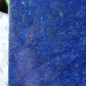May include: A close-up of a blue lapis lazuli stone. The stone has a rough, textured surface and a deep blue colour.