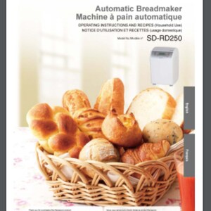 May include: A white Panasonic automatic breadmaker with the model number SD-RD250. The breadmaker is surrounded by a variety of freshly baked bread rolls in a wicker basket. The image is set against a white background.