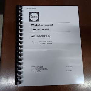 Może przedstawiać: Czarno-biały podręcznik warsztatowy do motocykla BSA A75 Rocket 3. Podręcznik obejmuje modele z lat 1969-1972 i zawiera logo BSA.