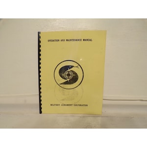 May include: Yellow operation and maintenance manual with a black and white logo of a snake wrapped around a target. The text "Military Armament Corporation" is printed below the logo.