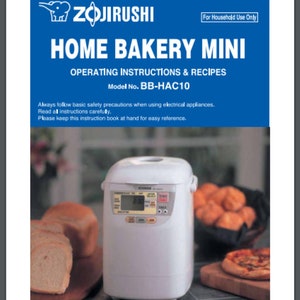 May include: White Zojirushi Home Bakery Mini bread maker with a digital display and control panel. The bread maker is on a countertop with a loaf of bread, a basket of rolls, and a pizza.