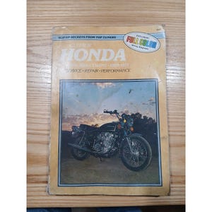Puede incluir: Un manual de reparación de motocicletas Honda Clymer. La portada presenta una motocicleta negra con el logotipo de Honda, sobre un paisaje. El manual incluye el texto "Hop-Up Secrets From Top Tuners" y "Full Color Wiring Diagrams".